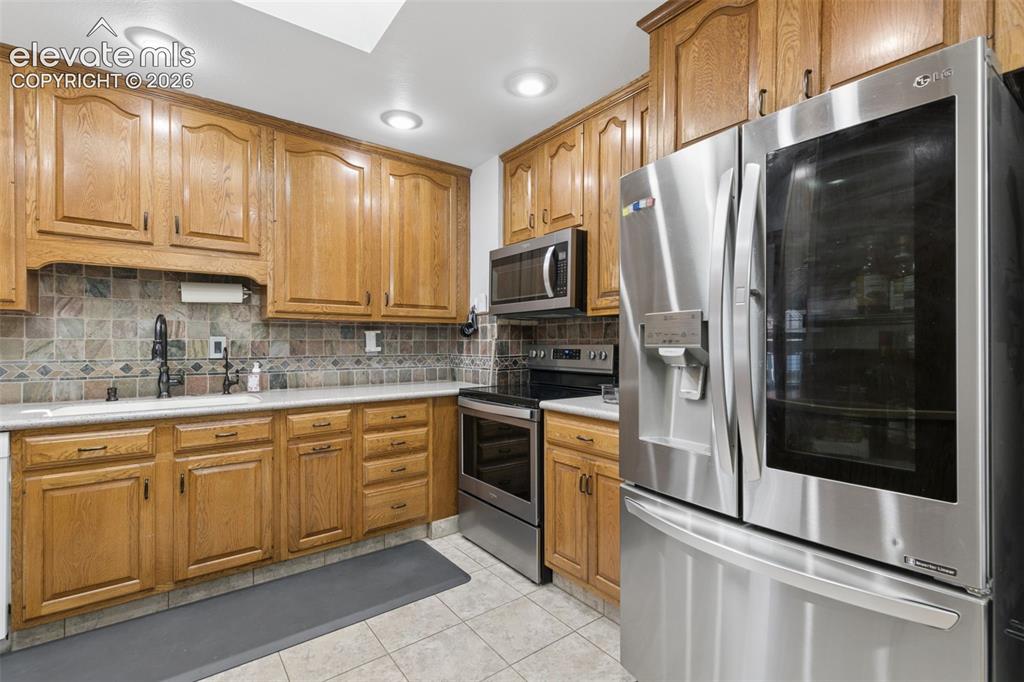Image 19 of 48: Kitchen with pull outs, solid countertops, backsplash and updated appliance
