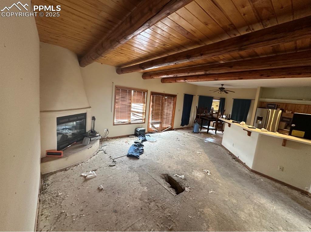 Image 11 of 36: Unfurnished living room with beamed ceiling and ceiling fan
