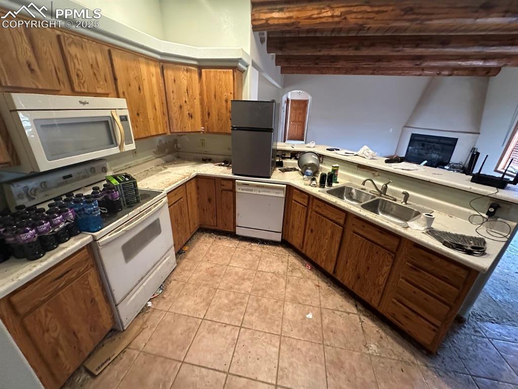 Image 15 of 36: Kitchen featuring brown cabinetry, white appliances, light countertops, bea