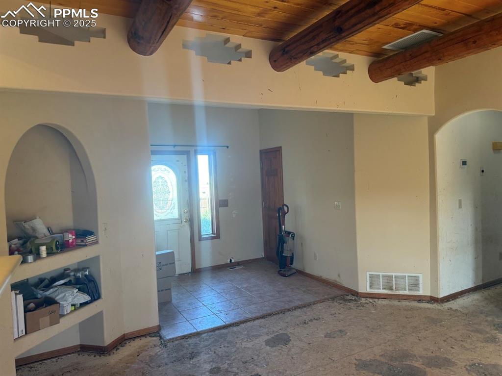 Image 16 of 36: Entrance foyer with a wooden ceiling with exposed beams and arched walkways