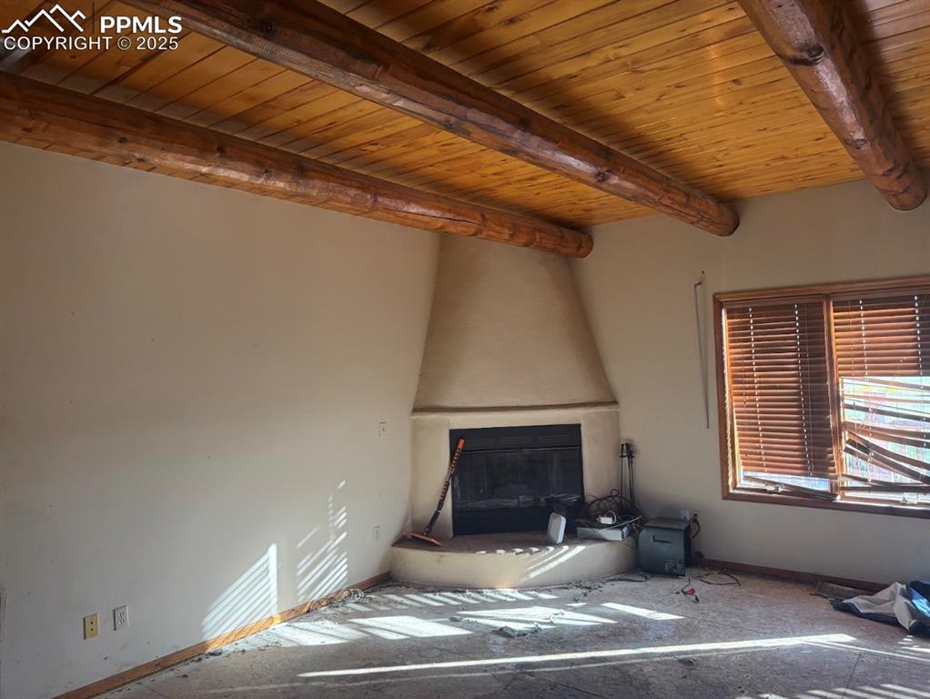 Image 17 of 36: Unfurnished living room featuring a wooden ceiling with exposed beams and a