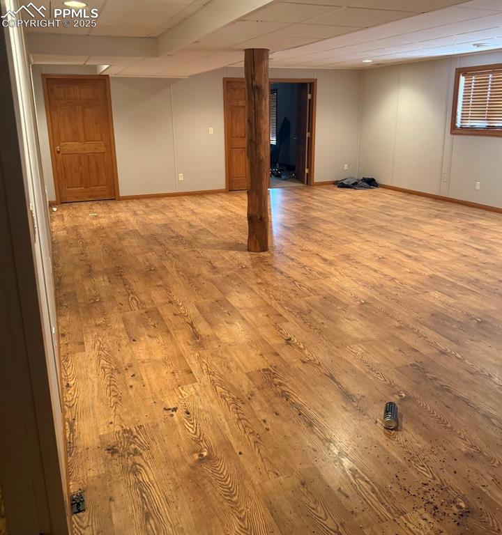 Image 36 of 36: Finished basement with a paneled ceiling and wood-type flooring