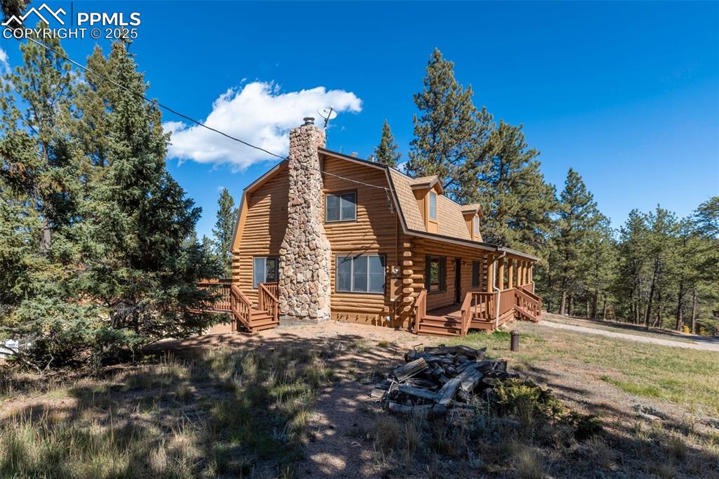 Image 10 of 50: View of front of property featuring a gambrel roof, log exterior, a chimney
