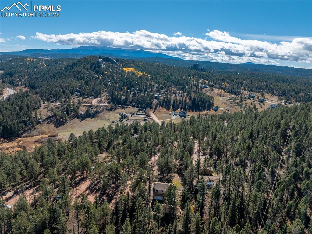 Image 13 of 50: Drone / aerial view of a mountainous background and a heavily wooded area