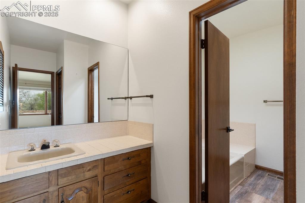 Image 17 of 23: Adjoining primary bath with large vanity and tub 