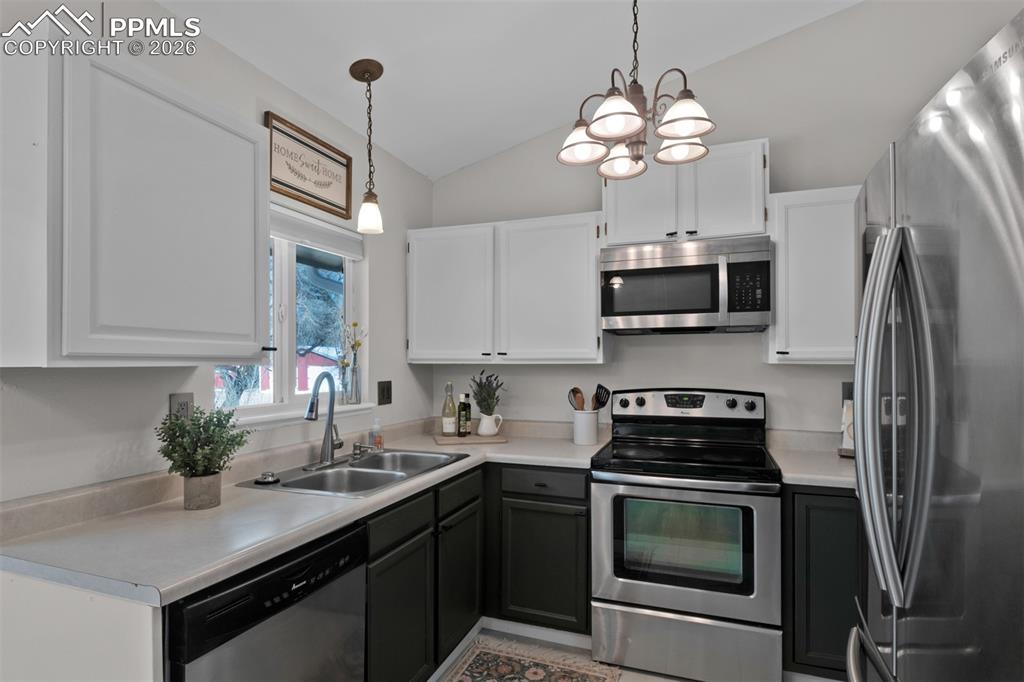 Image 14 of 42: Modern white and green painted cabinetry and stainless appliances. 