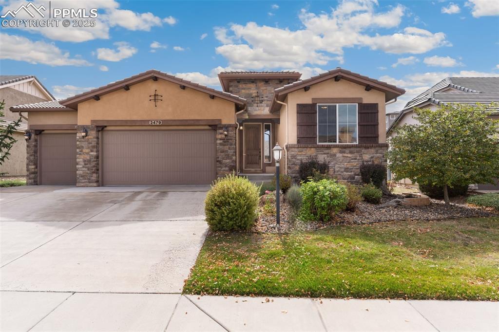 Caption: Mediterranean / spanish home featuring stucco siding, a garage, stone siding, and driveway