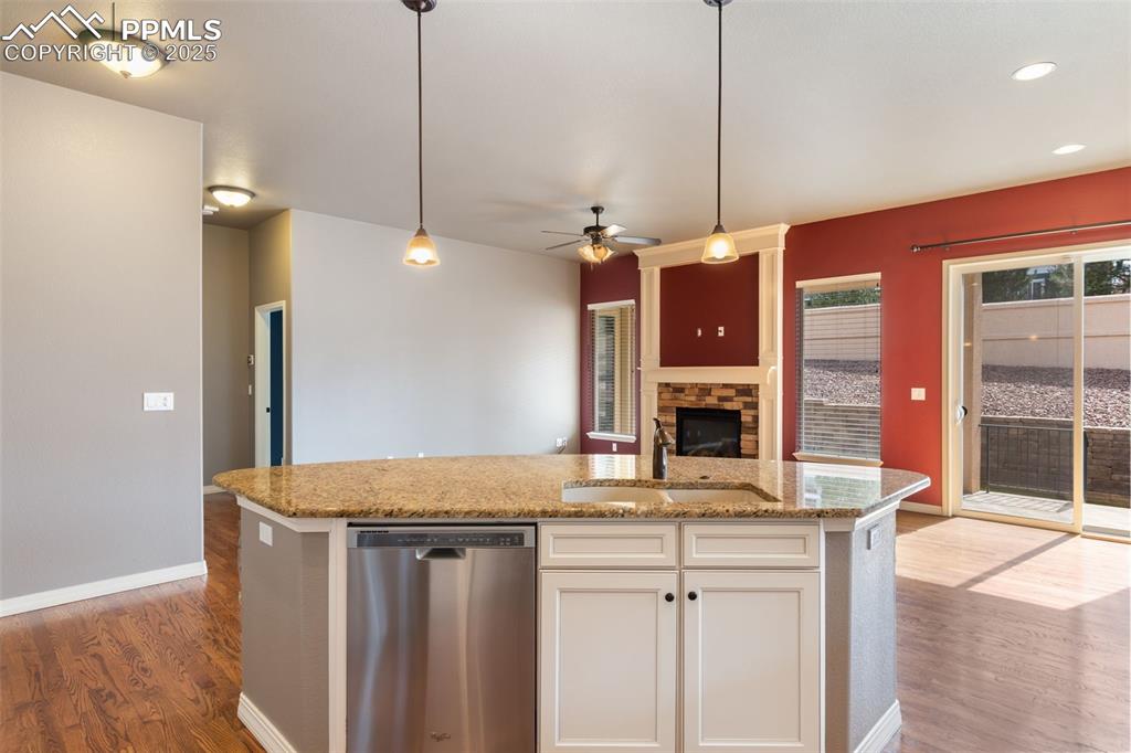 Image 11 of 27: Kitchen with a stone fireplace, stainless steel dishwasher, ceiling fan, li