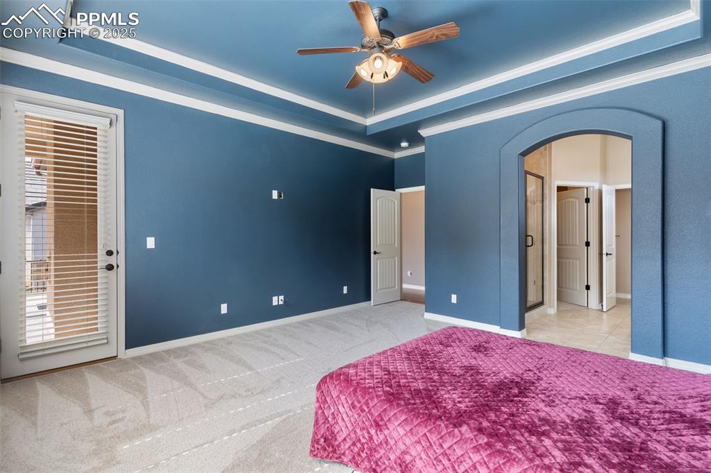 Image 15 of 27: Bedroom with a raised ceiling, arched walkways, carpet flooring, access to