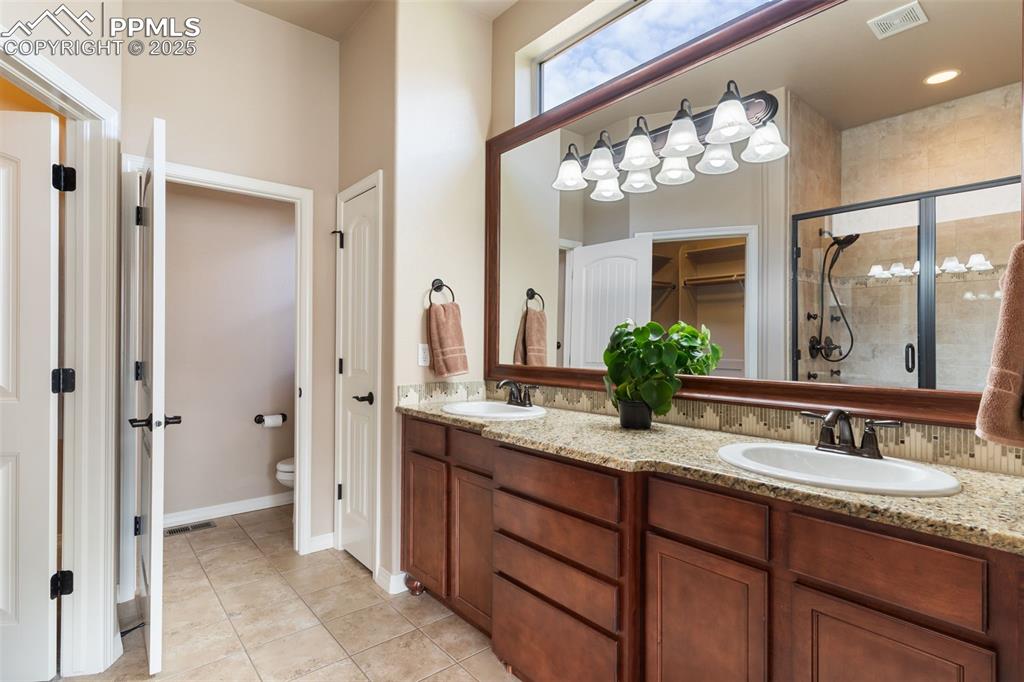 Image 16 of 27: Full bath with a shower stall, double vanity, and light tile patterned floo