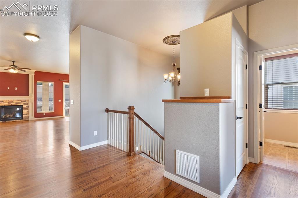 Image 3 of 27: Corridor with wood finished floors, a chandelier, and an upstairs landing