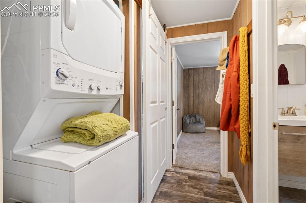 Image 17 of 25: Clothes washing area with stacked washer / drying machine, dark hardwood /
