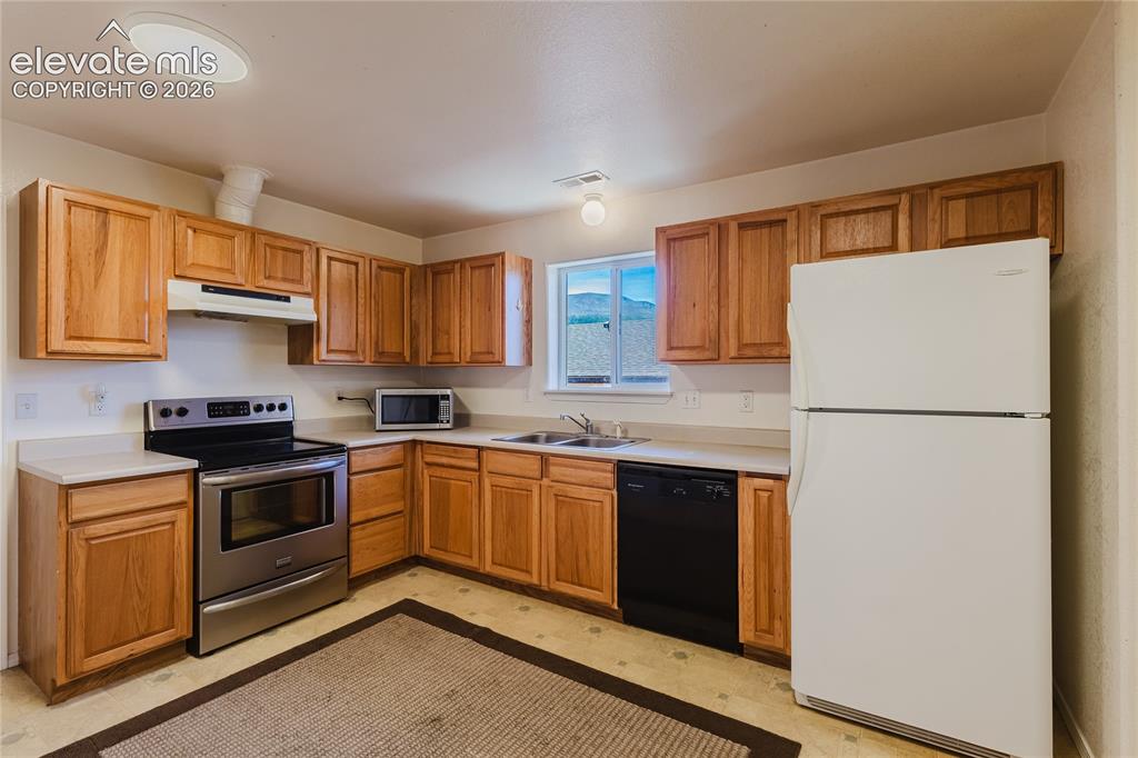Image 12 of 27: Eat-in kitchen featuring wood-finish cabinetry, laminate countertops, stain