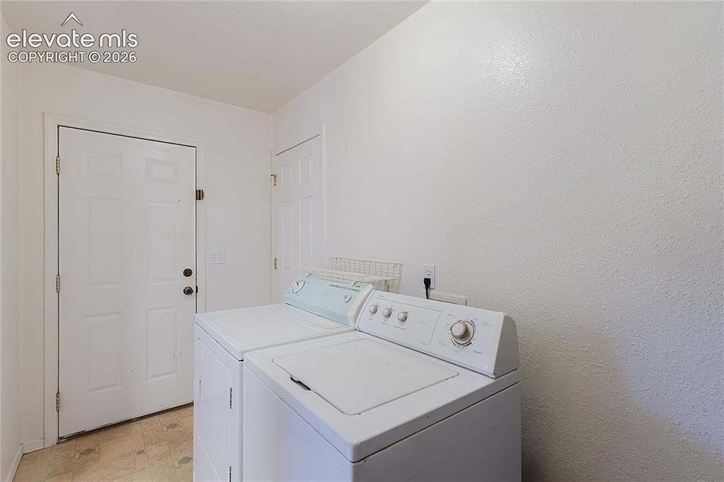 Image 15 of 27: Large laundry room with W/D and door to backyard and ground level deck