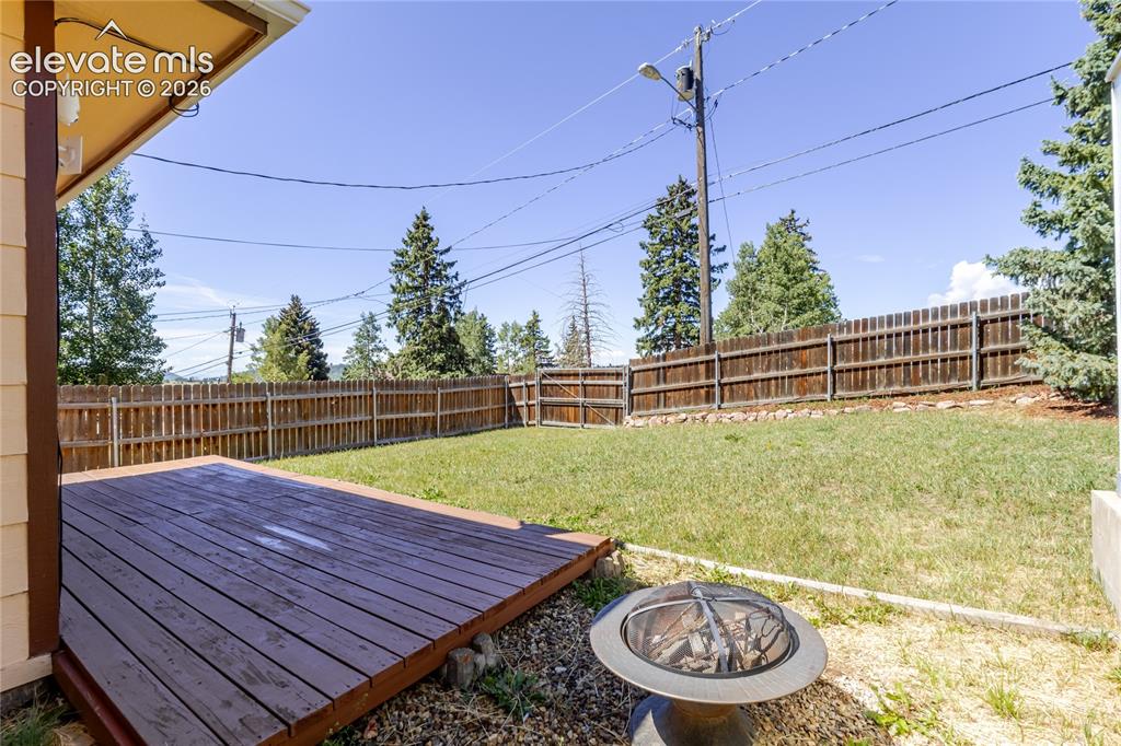Image 25 of 27: Backyard deck, lawn, raised beds with drip irrigation, and a separate gated