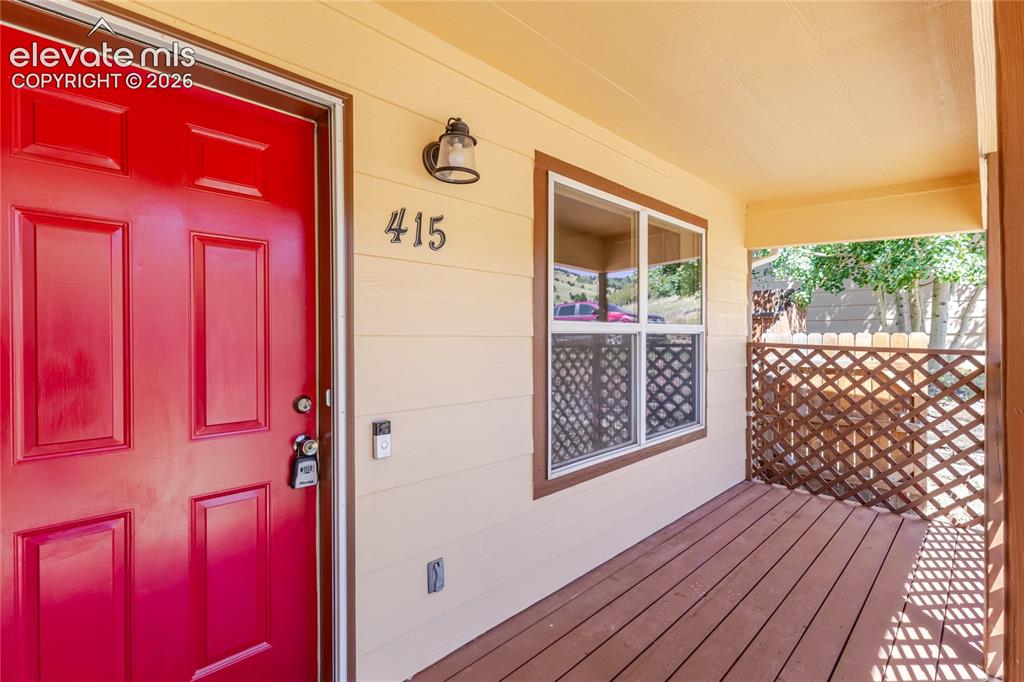 Image 3 of 27: Covered porch featuring a red entry door, horizontal siding, and wood-finis