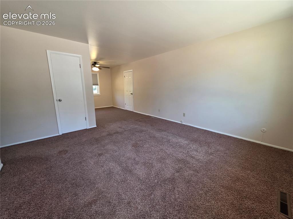 Image 4 of 17: Spacious room featuring neutral-toned walls, brown carpet flooring, and whi