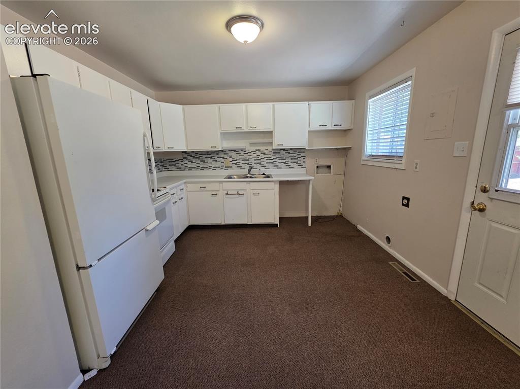 Image 7 of 17: Kitchen featuring white cabinetry, white appliances, a tile backsplash, and