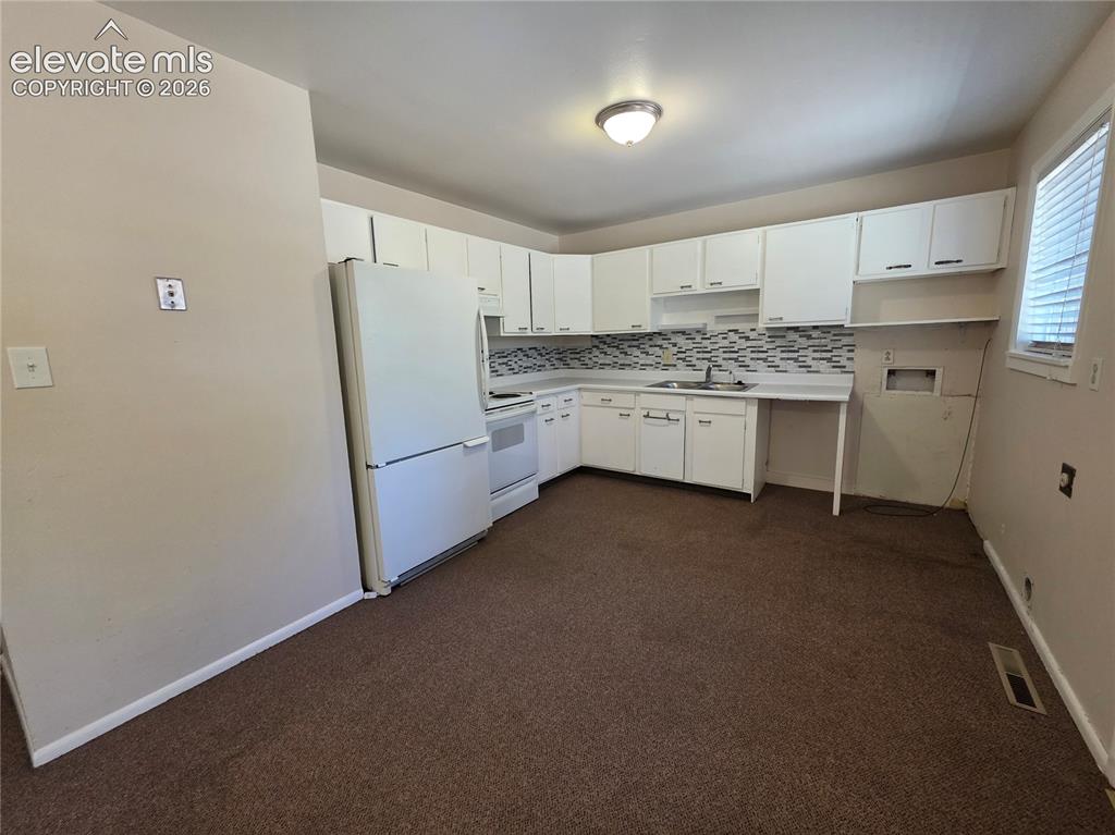 Image 8 of 17: Kitchen featuring white cabinetry, white appliances, a tile backsplash, and