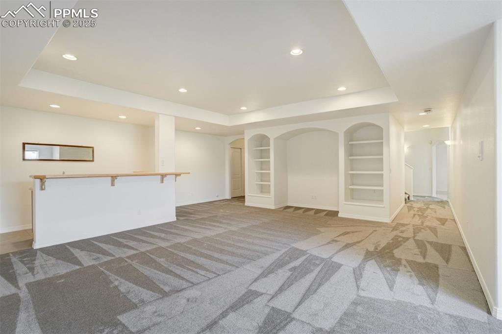 Image 34 of 50: Basement family room with wet bar view and TV niche.