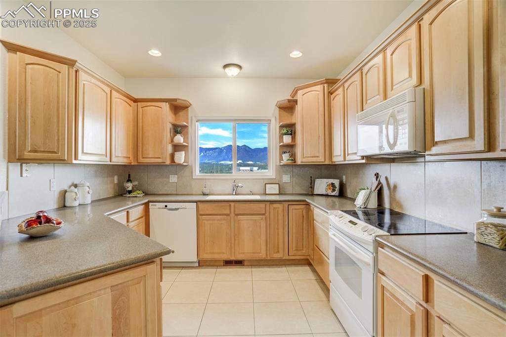Image 7 of 50: The kitchen features a beautiful Mountain View, oak cabinets, solid surface