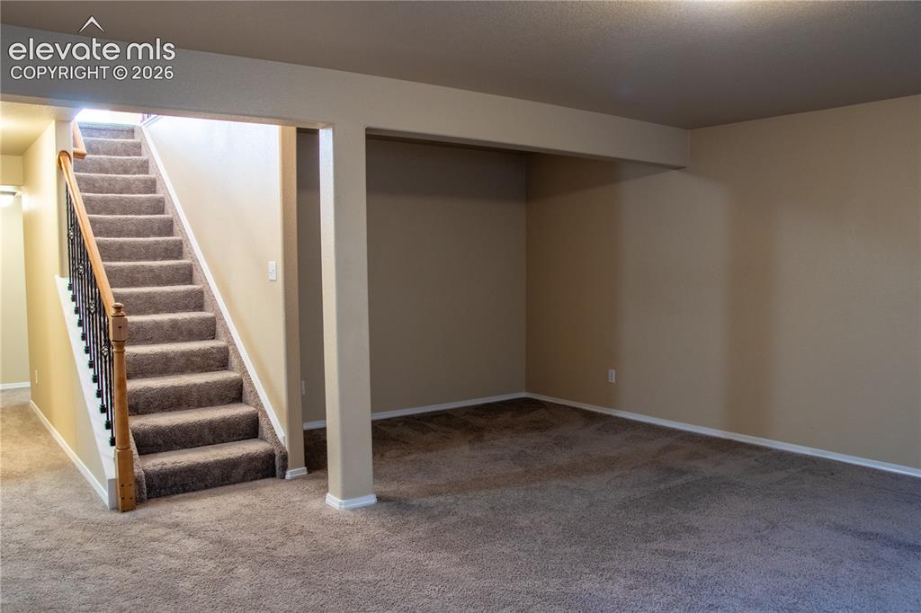 Image 20 of 40: Carpeted staircase with an ornamental metal baluster and wood-finish handra
