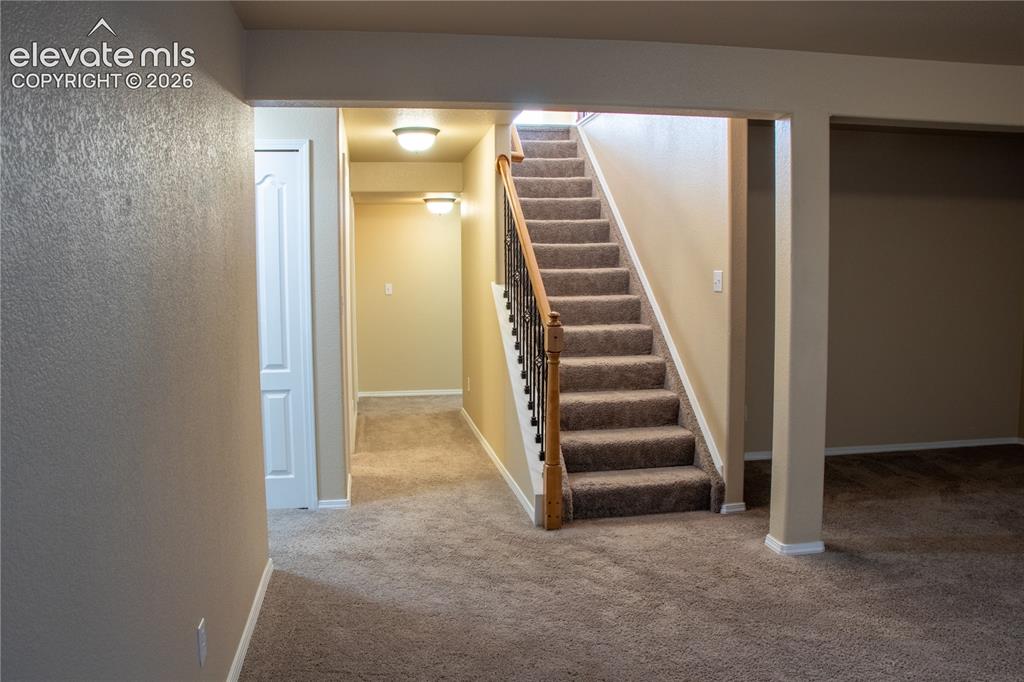 Image 21 of 40: Carpeted staircase with wood handrail and wrought iron balusters, complemen