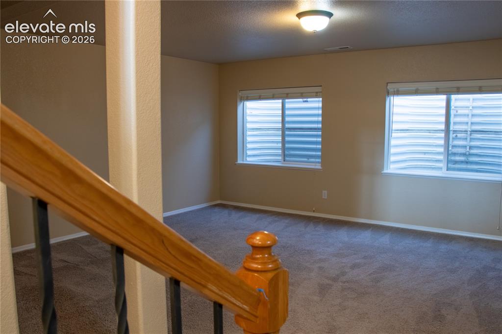 Image 23 of 40: Carpeted room featuring two windows with horizontal blinds, light beige wal