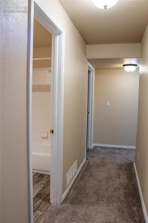 Image 29 of 40: Neutral tone walls and carpeting create a cohesive corridor, illuminated by