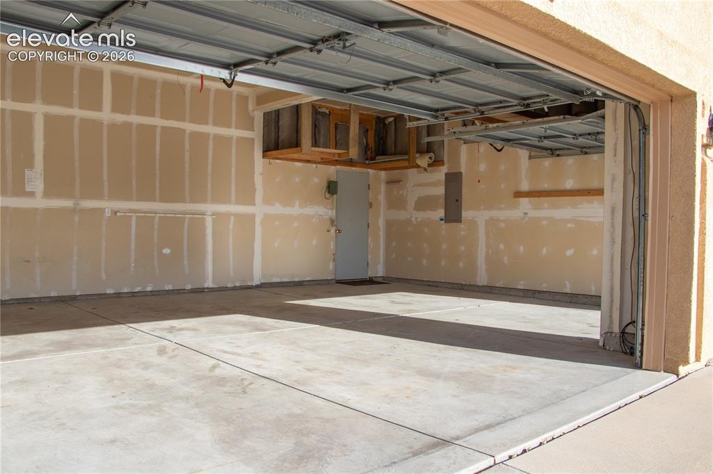 Image 36 of 40: Spacious garage featuring a concrete floor, an overhead garage door mechani