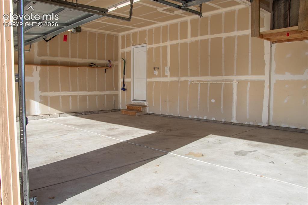 Image 37 of 40: Two-car garage featuring a concrete floor, unpainted drywall with taped sea