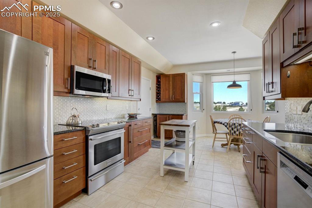 Image 14 of 50: Kitchen with tasteful backsplash, tile floors, updated light fixtures, and