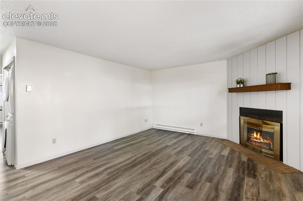 Image 12 of 33: Living area featuring wood-finish flooring, a fireplace with a brass-trimme