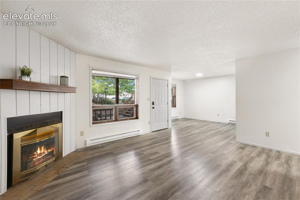 Image 13 of 33: Open living space featuring wood-finish flooring and a fireplace with a woo