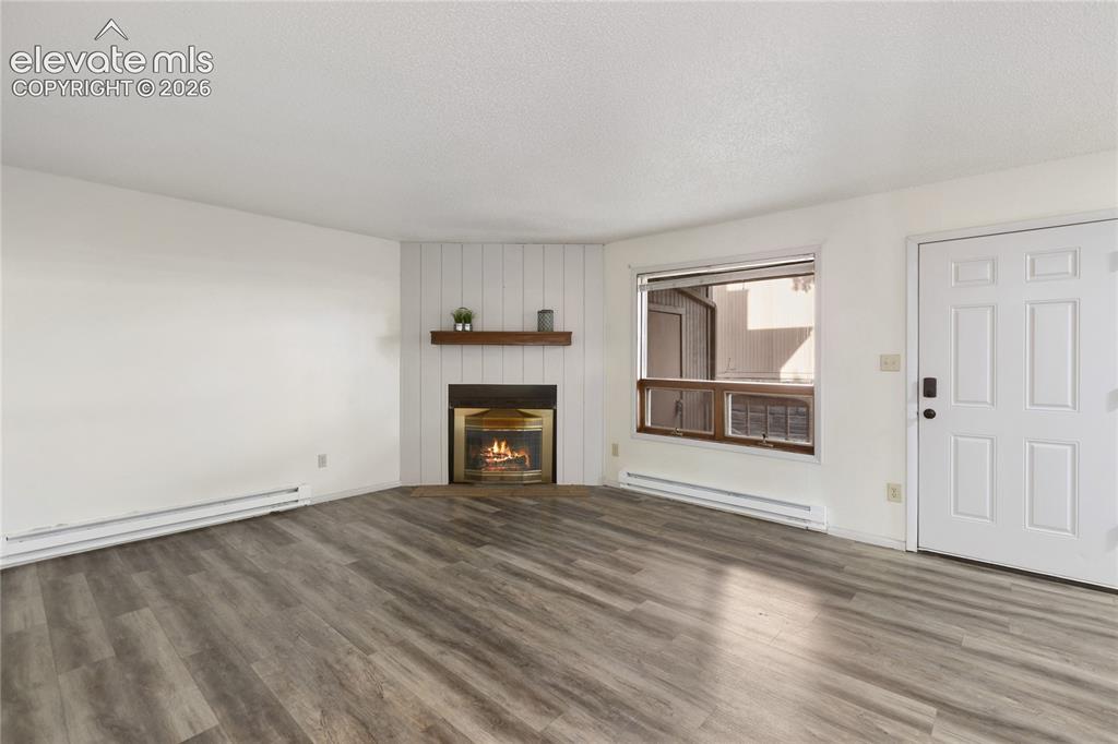 Image 14 of 33: Living area featuring wood-finish flooring, a corner fireplace with a wood
