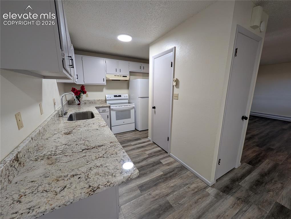 Image 18 of 33: Kitchen featuring light-colored granite countertops, white cabinetry with b