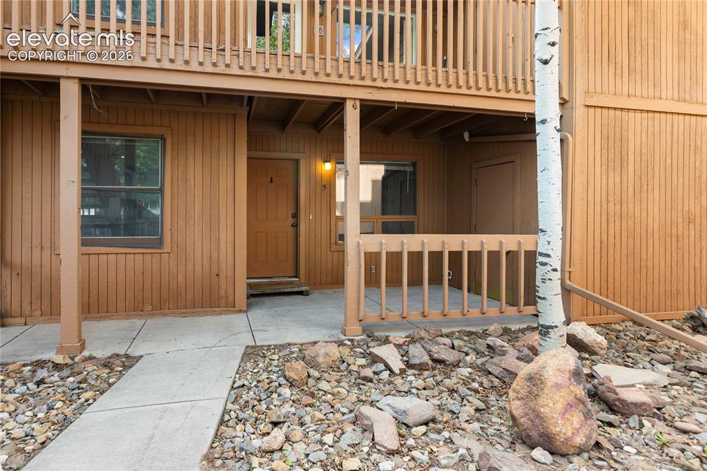 Image 2 of 31: Ground-level entrance featuring a wood-paneled exterior, concrete walkway,