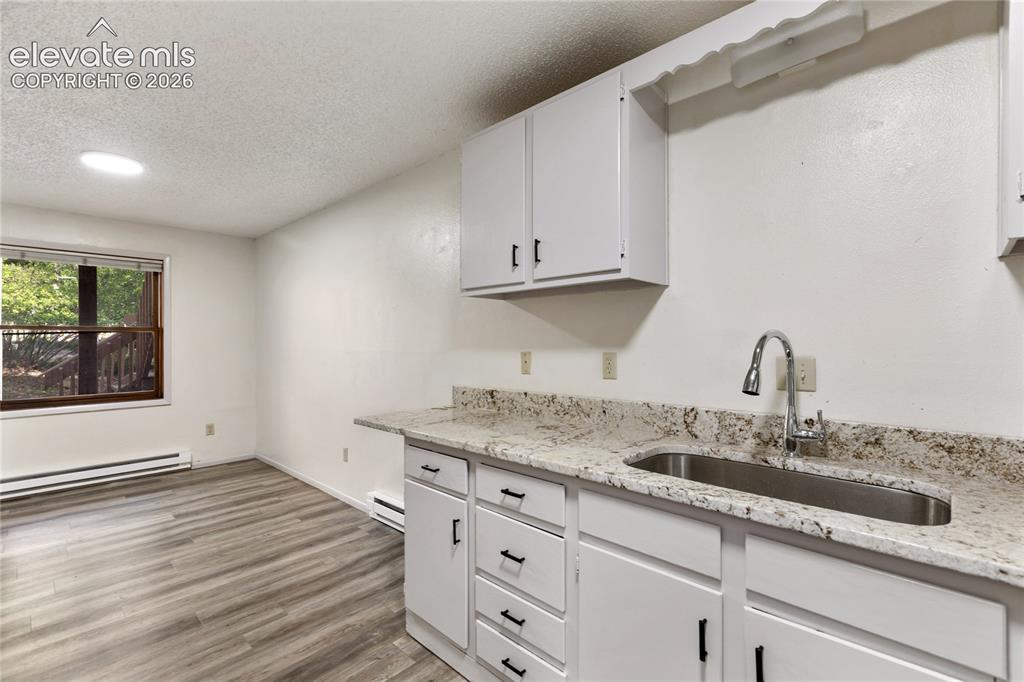 Image 20 of 33: Compact kitchenette featuring white cabinetry, a speckled countertop, and a