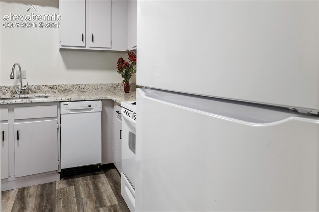 Image 21 of 33: Kitchen featuring white cabinetry, speckled countertops, a gooseneck faucet