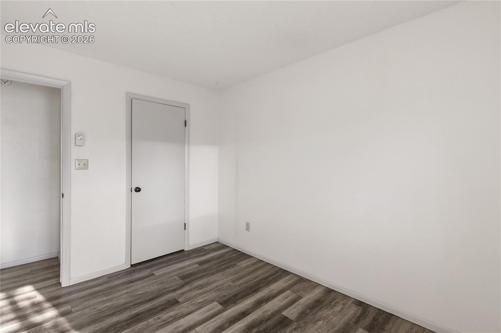 Image 25 of 33: Neutral white walls with wood-finish flooring