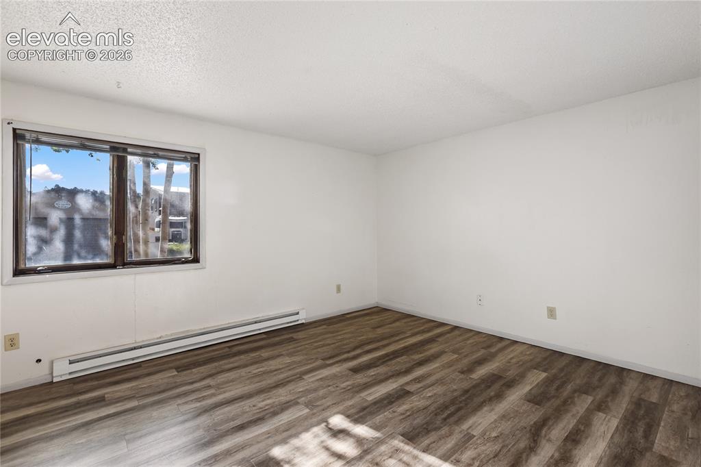 Image 26 of 33: Spacious room featuring wood-finish flooring and white painted walls