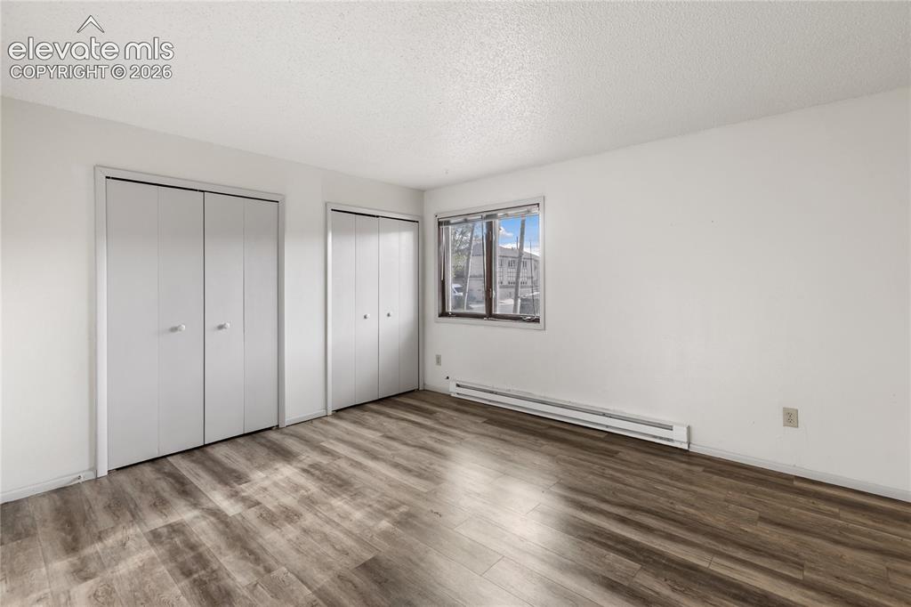 Image 6 of 33: Room featuring wood-finish flooring, white walls, and a textured ceiling