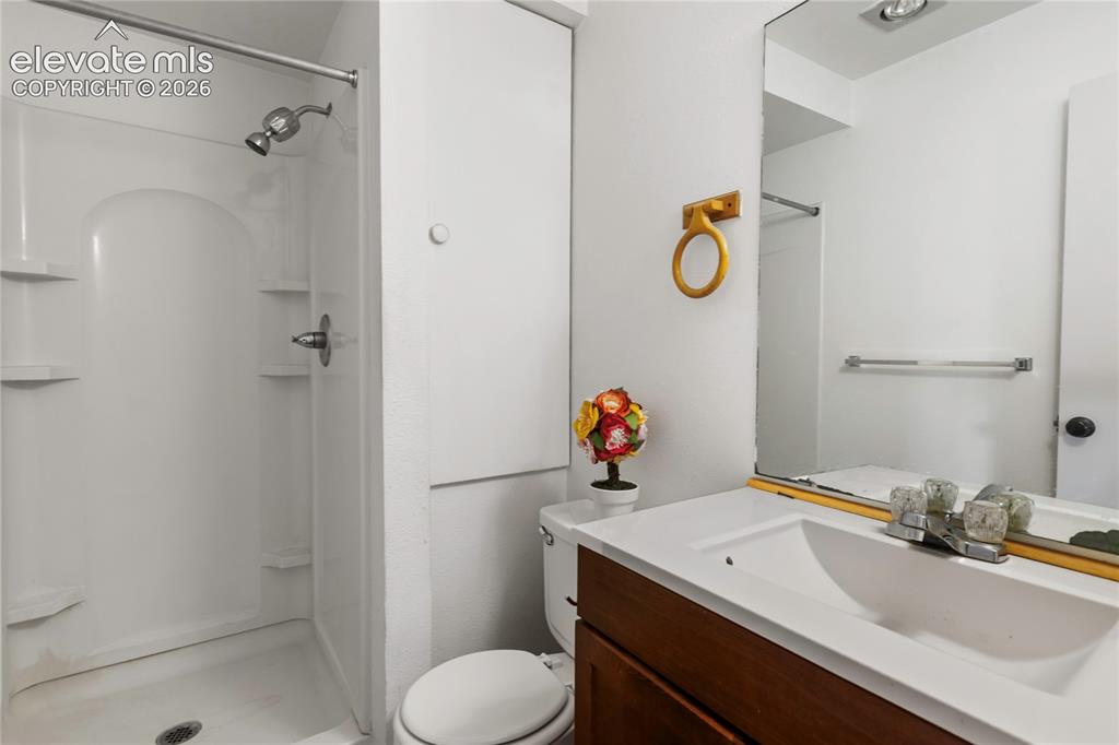 Image 7 of 33: Bathroom featuring a white shower stall with built-in shelving, a wood-fini