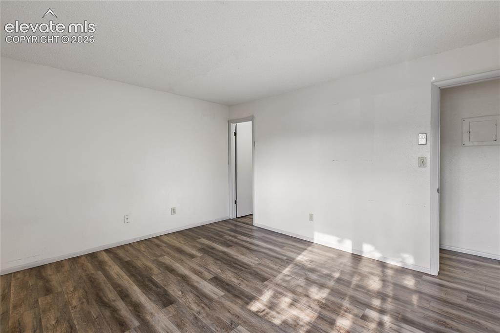 Image 8 of 33: Spacious room featuring wood-finish flooring, white painted walls, and a te