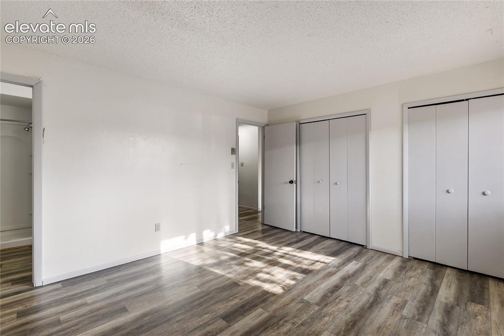 Image 9 of 33: Room featuring wood-finish flooring, two sets of bi-fold closet doors, a fl