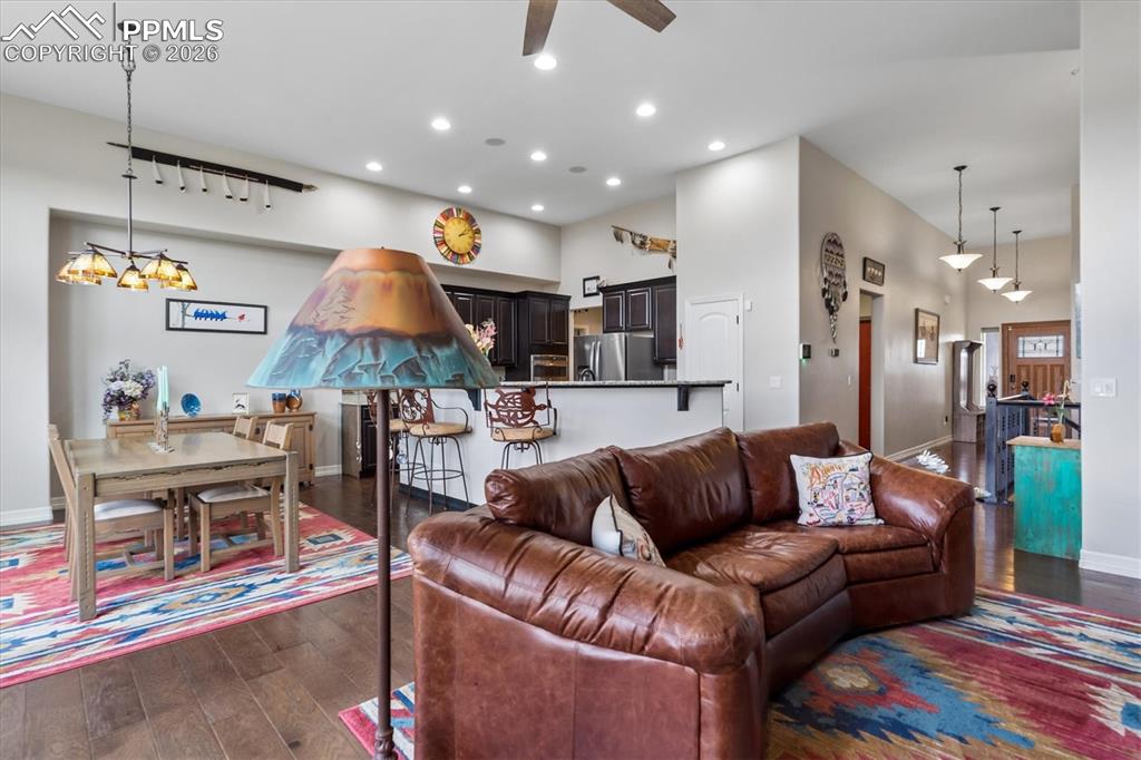 Image 12 of 48: Living room with dark wood-style floors, a fireplace, a ceiling fan, and a