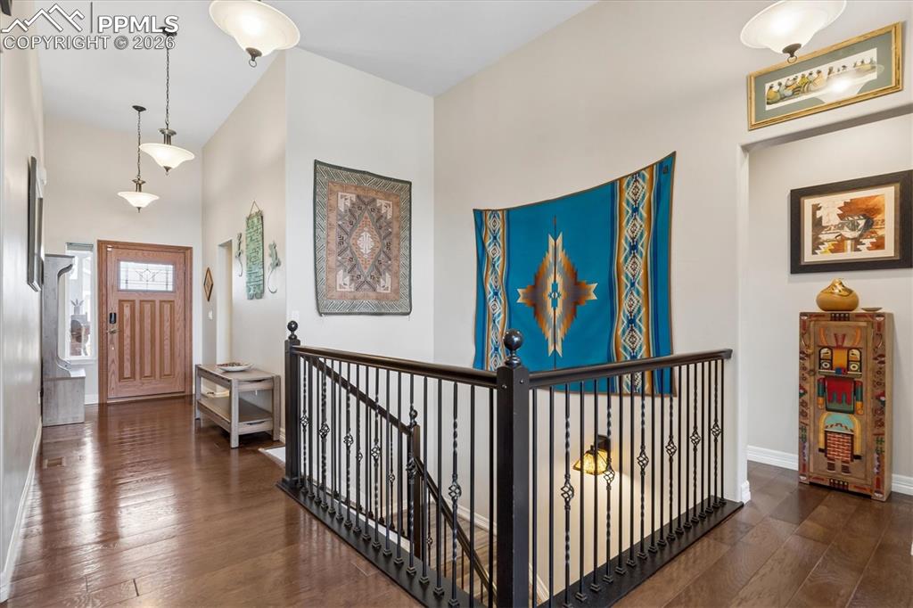 Image 16 of 48: Dining room with wood finished floors, hanging lights, and a high ceiling