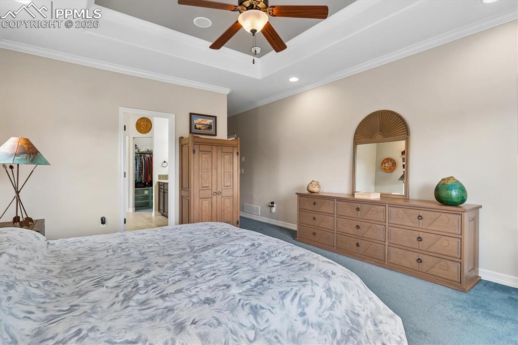Image 19 of 48: Carpeted bedroom with ornamental molding, ceiling fan, connected bathroom,