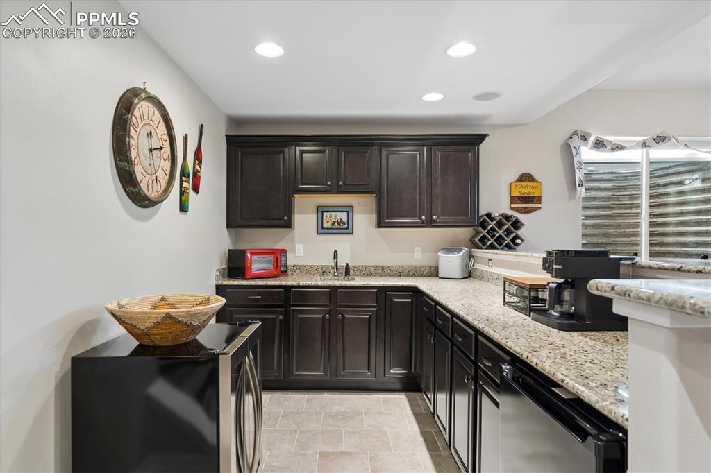 Image 37 of 48: Kitchen with a peninsula, dishwasher, light stone countertops, recessed lig