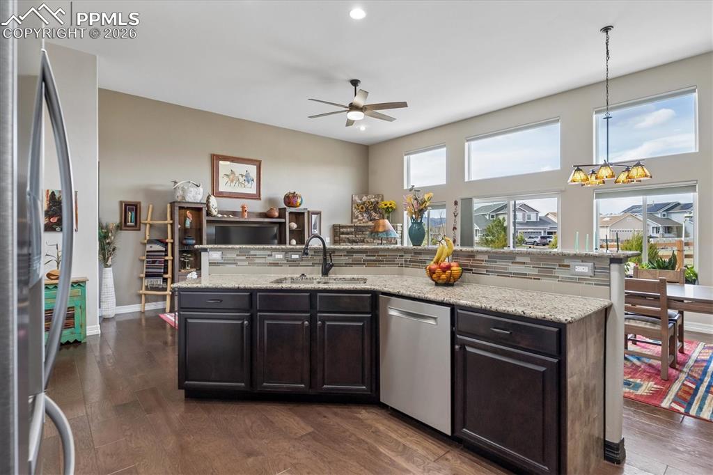 Image 9 of 48: Kitchen featuring dark wood finish cabinetry, a kitchen island with sink, s